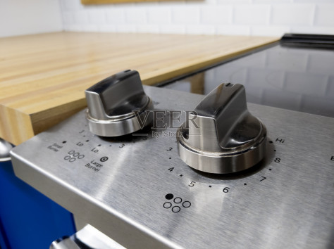 两个控制旋钮上的玻璃炉顶在一个干净的厨房与木制台面照片摄影图片