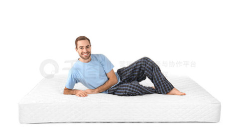 一个年轻人躺在白色背景下的床垫上