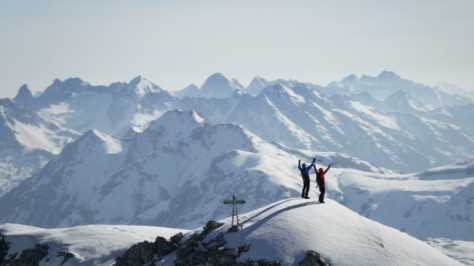 登山者在白雪覆盖的山峰上欢欣鼓舞