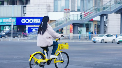 女子骑美团共享单车驶过