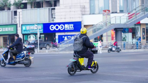 男子背书包骑行电瓶车