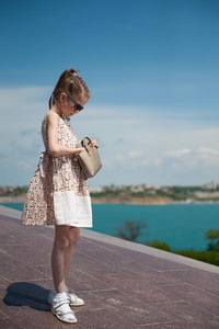 时髦的小的女孩使人疲乏的衣服和太阳镜有样子的为det.一些 照片