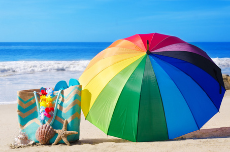 夏天背景与彩虹伞和沙滩袋照片