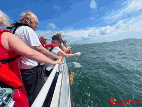 “里斯本丸”号船英军战俘后人将白色花瓣洒向蔚蓝的大海。人民网记者 王丽玮摄