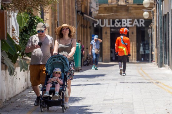 6月4日，人们戴着帽子走在塞浦路斯首都尼科西亚街头。新华社发（乔治·克里斯托弗鲁摄）