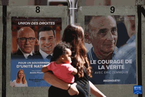 6月30日，在法国巴黎附近的克里希，一对母子走过街头的竞选海报。新华社记者 高静 摄