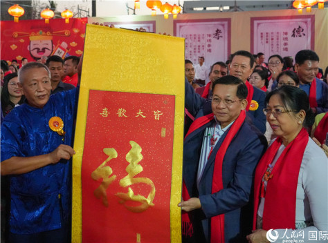 2024年2月18日，敏昂莱主席夫妇在“锦绣唐人街”新春庆典活动现场体验中国传统书法艺术。人民网记者谢佳君摄