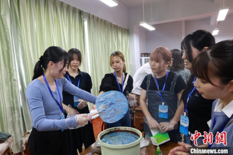 中国伝統工芸のマーブリングで作る団扇の「漆扇」作りを体験する日本の若者（撮影・林馨）。