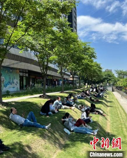 正午に上海市徐匯区の地下鉄・雲錦路駅付近の芝生の上で寝転ぶ若者たち（写真提供・取材対応者）。