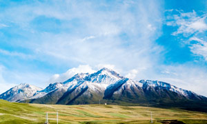 蓝天白云下的雪山和草地摄影图片