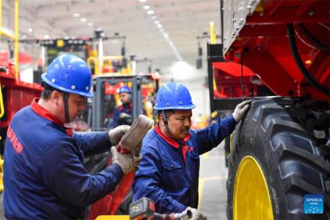 Amatjan Mamat monte un pneu sur la roue d'une récolteuse de coton dans une usine de récolte de coton à Wusu, dans la région autonome ouïgoure du Xinjiang (nord-ouest de la Chine), le 28 février 2024. (Zhao Ge / Xinhua)