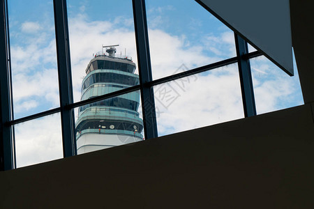 机场候机楼望向窗外机场交通管制塔剪影和美丽的蓝天图片